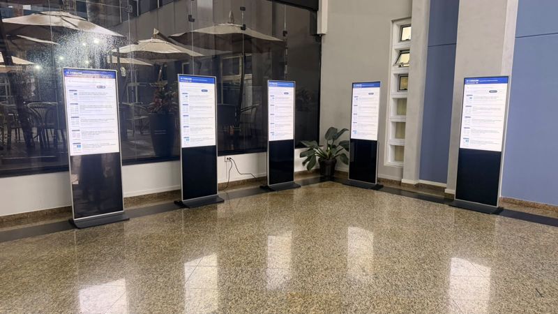 Área de pôsteres com totens de e-pôster lado a lado, cada um com a busca por título ou autor